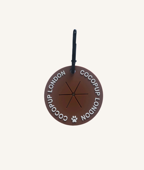 Support sac crottes chien marron en silicone, fixé sur une laisse lors d’une promenade